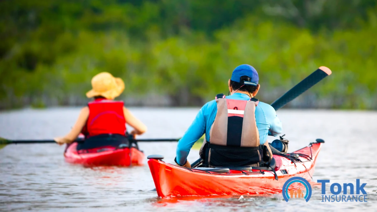 Two kayakers in life vests paddling red and blue kayaks on calm water